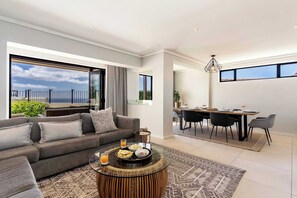A modern living room with a sofa, coffee table, and dining area with chairs and a table.
