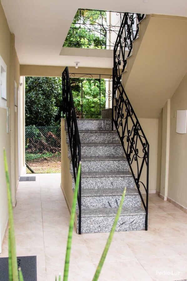 A staircase with black metal railings leading to a landing. - Apart Sol Nascente (Itatiaia)