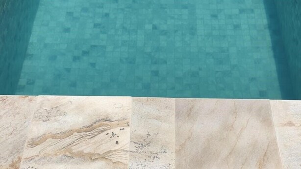 Una piscina con suelo y borde de baldosas.