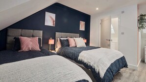 Ein Schlafzimmer mit zwei Betten, dunklen Wänden und einer schrägen Decke.