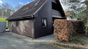 A log cabin with a sloped roof, a balcony, and a small window. - Inchmurrin Lodge with private hot tub (Drymen)