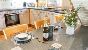 A kitchen with a dining area set for a meal. - Inchmurrin Lodge with private hot tub (Drymen)