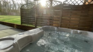 A hot tub with a wooden deck and a fence, surrounded by a grassy yard. - Inchmurrin Lodge with private hot tub (Drymen)