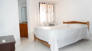 Une chambre à coucher avec un lit en bois, des rideaux blancs et une commode en bois.