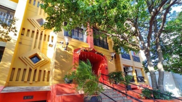 Un bâtiment à la façade jaune, avec une porte d’entrée rouge et un escalier menant à l’entrée.