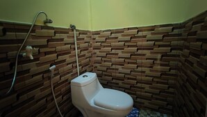 Une petite salle de bain avec des toilettes, une douche et un sol carrelé.