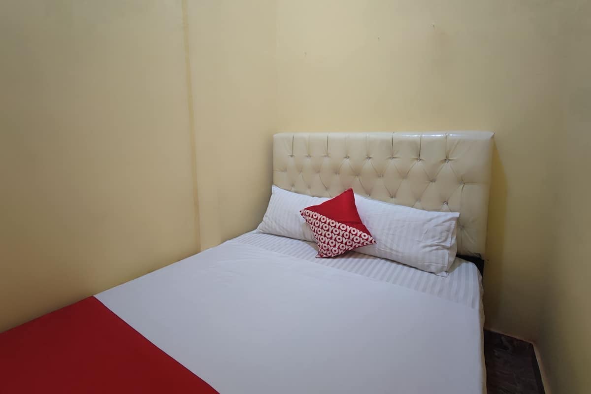 A neatly made bed with a white and red bedspread, a tufted headboard, and a single red pillow.