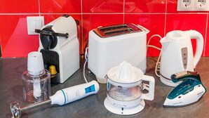 A kitchen with a red tiled backsplash, a toaster, a kettle, a juicer, an electric toothbrush, and an iron. - Apartamento en Pleno Centro de Navacerrada (Navacerrada)