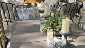 A sunlit patio with wicker furniture, a wooden table, and candles. - Great Waters gem! Spacious Waterfront Cottage! Family Friendly Getaway! (Eatonton)