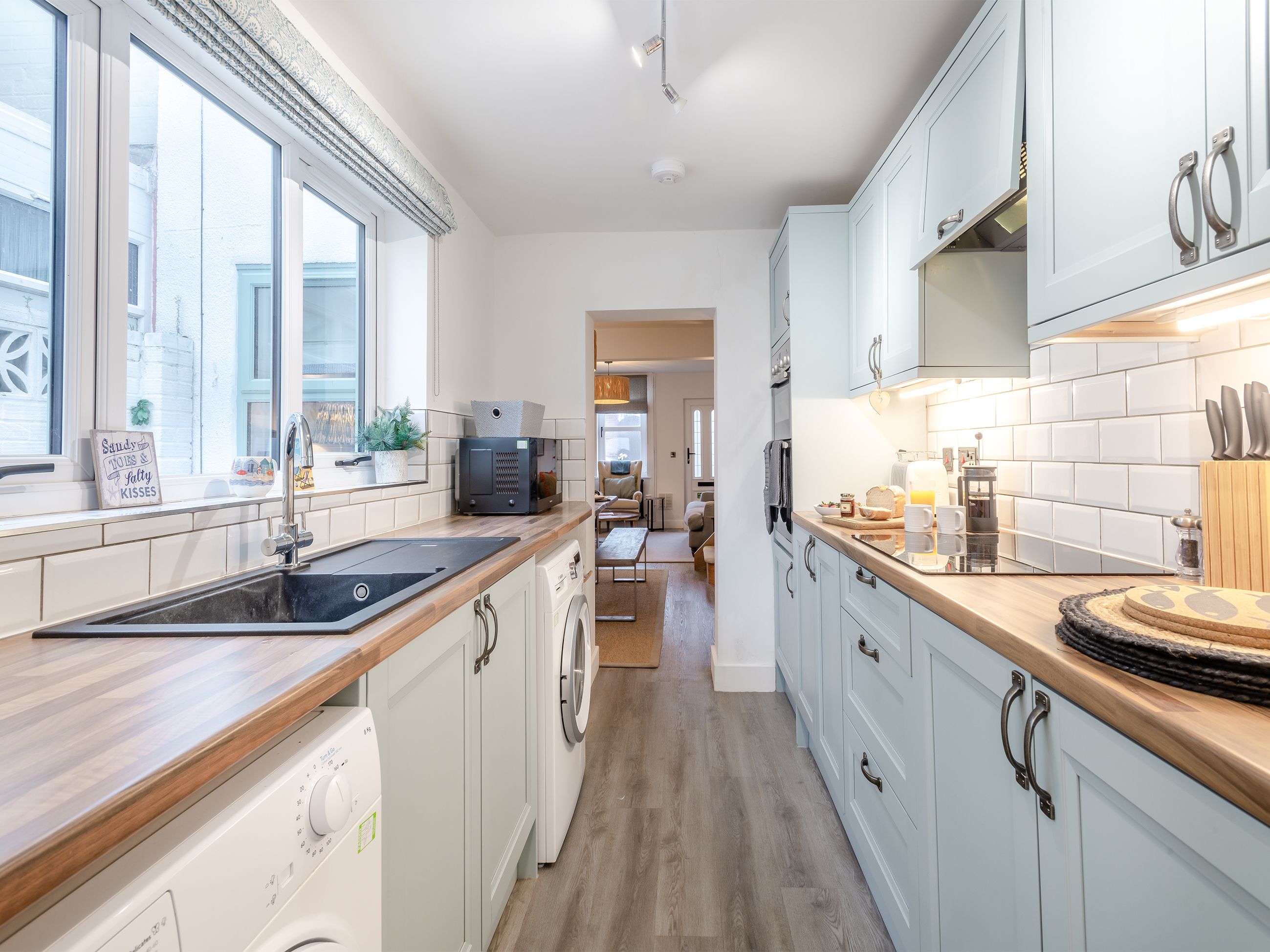A modern kitchen with a wooden countertop, stainless steel appliances, and a view into the dining area.