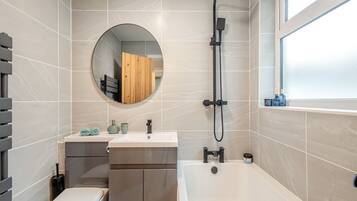 Un baño moderno con inodoro, lavabo, tocador, bañera, ducha y un espejo grande.