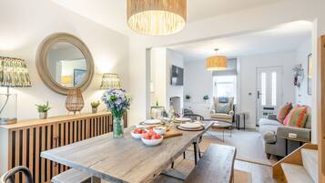 A modern living room with a wooden dining table, a sofa, and a large mirror.