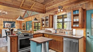 A rustic kitchen with wooden cabinets, a large stove, and a sink.
