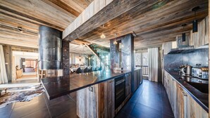 A spacious kitchen with a large island, wooden ceiling beams, and modern appliances.