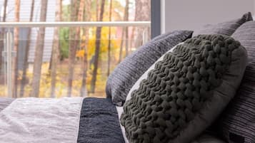 A bed with multiple pillows and a view of trees through a window.