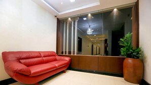 Un interior moderno con un sofá de cuero rojo, una planta grande en maceta y un separador de vidrio.
