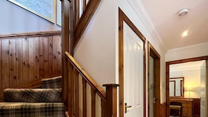 Un escalier avec des rampes en bois et un palier recouvert d’une moquette à carreaux.