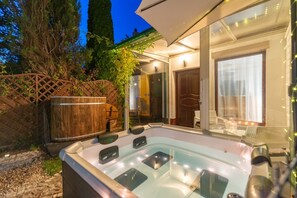 Un jacuzzi con muelle de madera y un barril de madera, rodeado por una valla de madera y árboles.