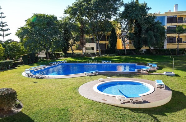 Une piscine avec des chaises longues, un jacuzzi rond et une pelouse bien entretenue.