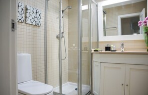Une salle de bain moderne avec une douche à parois de verre, des toilettes et un meuble-lavabo avec un miroir.