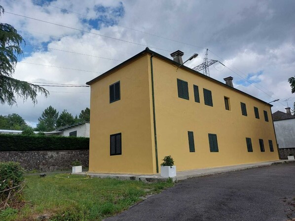 A two-story yellow building with multiple windows and a chimney.