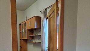 A room with a wooden wardrobe, a small desk, and a potted plant. - Apartamento Rural en Plena Ribeira Sacra (Cerreda)