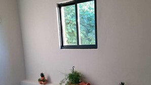 A staircase with a handrail, a window with a view of greenery, and a shelf with potted plants. - Apartamento Rural en Plena Ribeira Sacra (Cerreda)