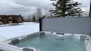 Boblebad med kontrolpanel, omgivet af en træterrasse.