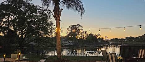 A garden patio with a pathway, chairs, and string lights.