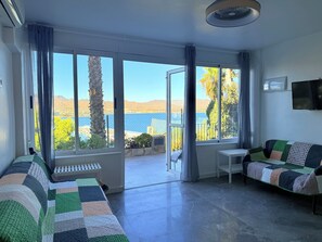 Um quarto com uma janela grande, um sofá, uma mesa pequena e um radiador.