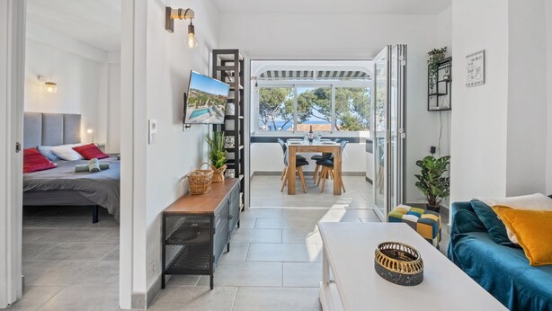 Un salon moderne avec un canapé, une table à manger et un téléviseur fixé au mur.