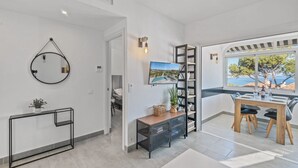 Une chambre d’hôtel moderne dotée d’un miroir rond, d’une télévision, d’un coin repas avec vue sur la mer et d’un escalier.