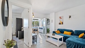Un salon moderne avec un canapé bleu, une table basse blanche et un coin repas comprenant une table et des chaises.