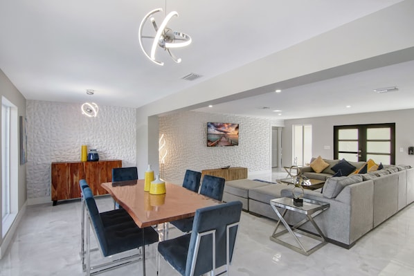 Una sala de estar moderna con comedor, un sofá gris y una mesa de comedor de madera con sillas.