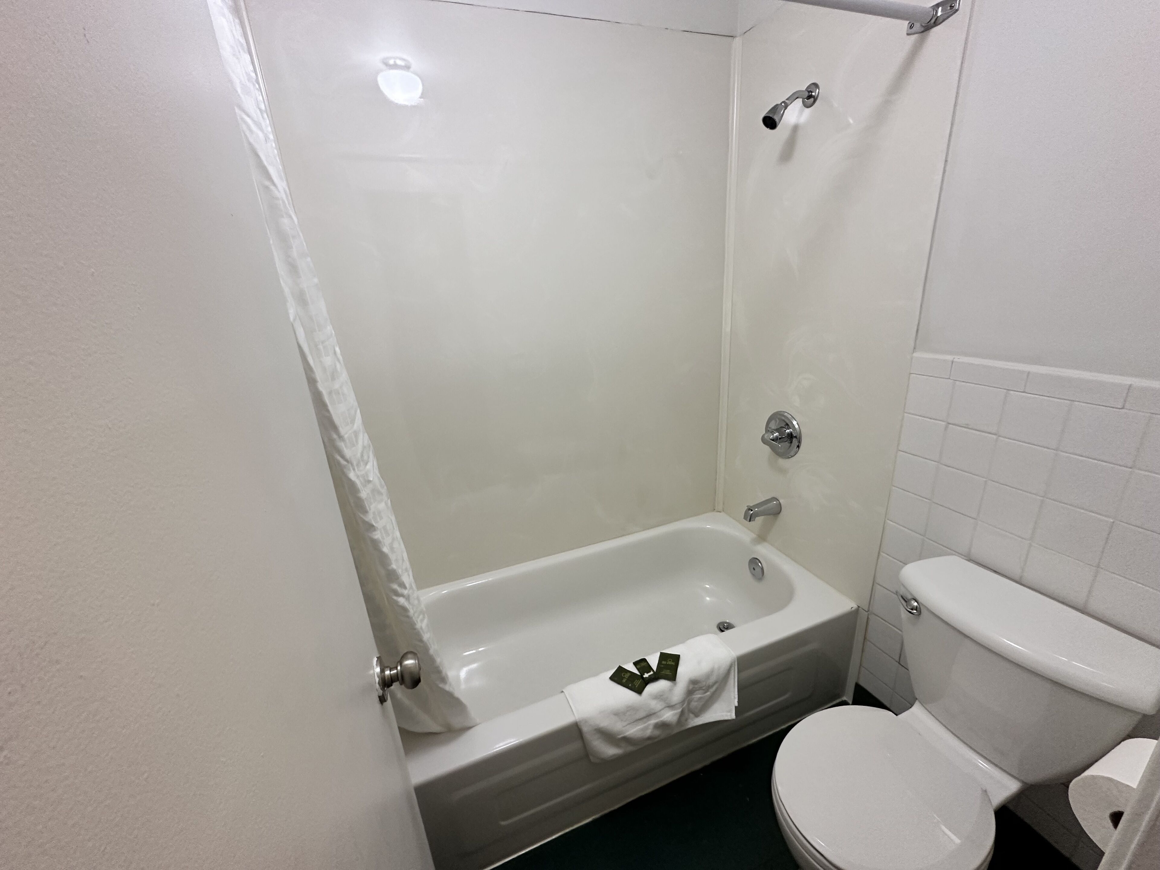 Et badeværelse med badekar, toilet og bruser.