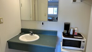 A bathroom with a sink, mirror, and a coffee maker.