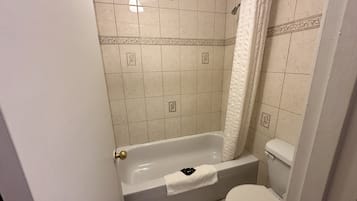 A bathroom with a bathtub, toilet, and shower curtain.