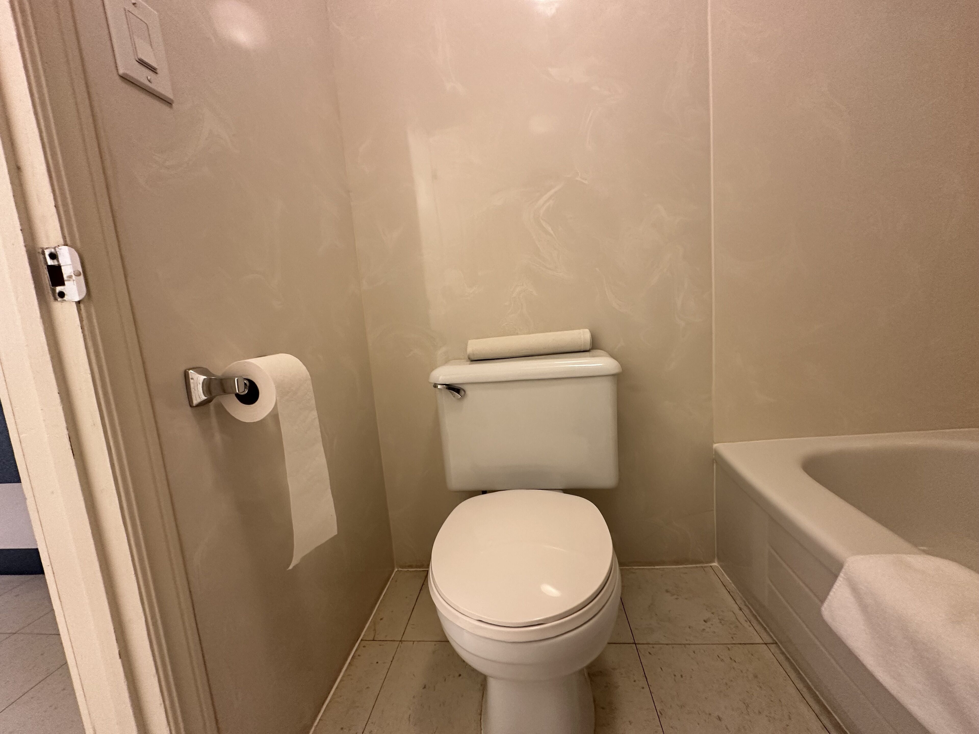 A small, clean bathroom with a toilet, a roll of toilet paper, and a bathtub.