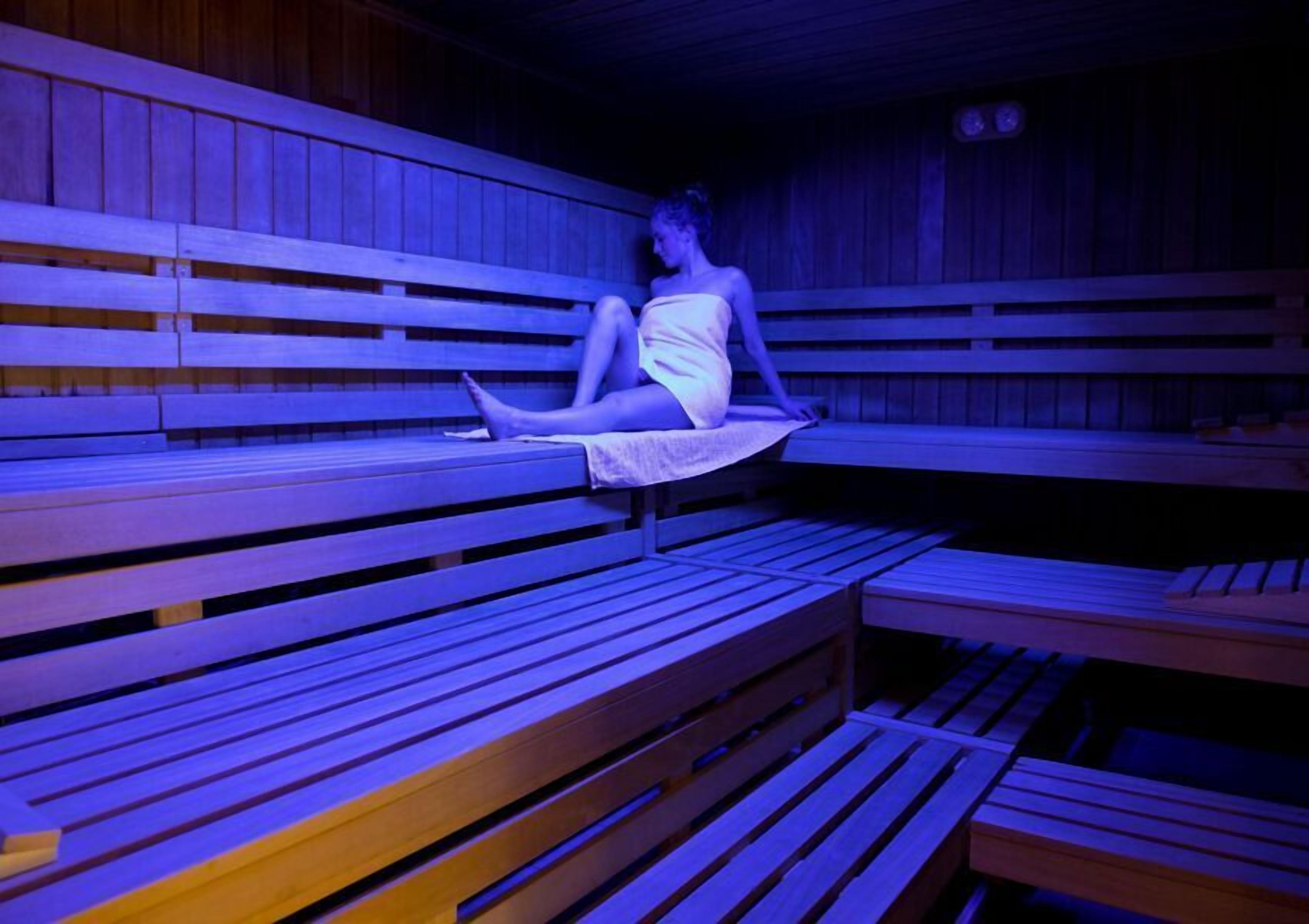 A sauna with wooden benches and a person sitting on one.