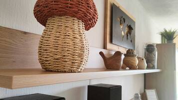 Een werkplek aan huis met een grote geweven lamp, een ingelijst kunstwerk en een plank met decoratieve objecten.