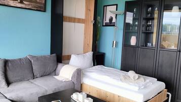 Una sala moderna con sofá, cama, mesa de centro y un aparador con puertas de vidrio.
