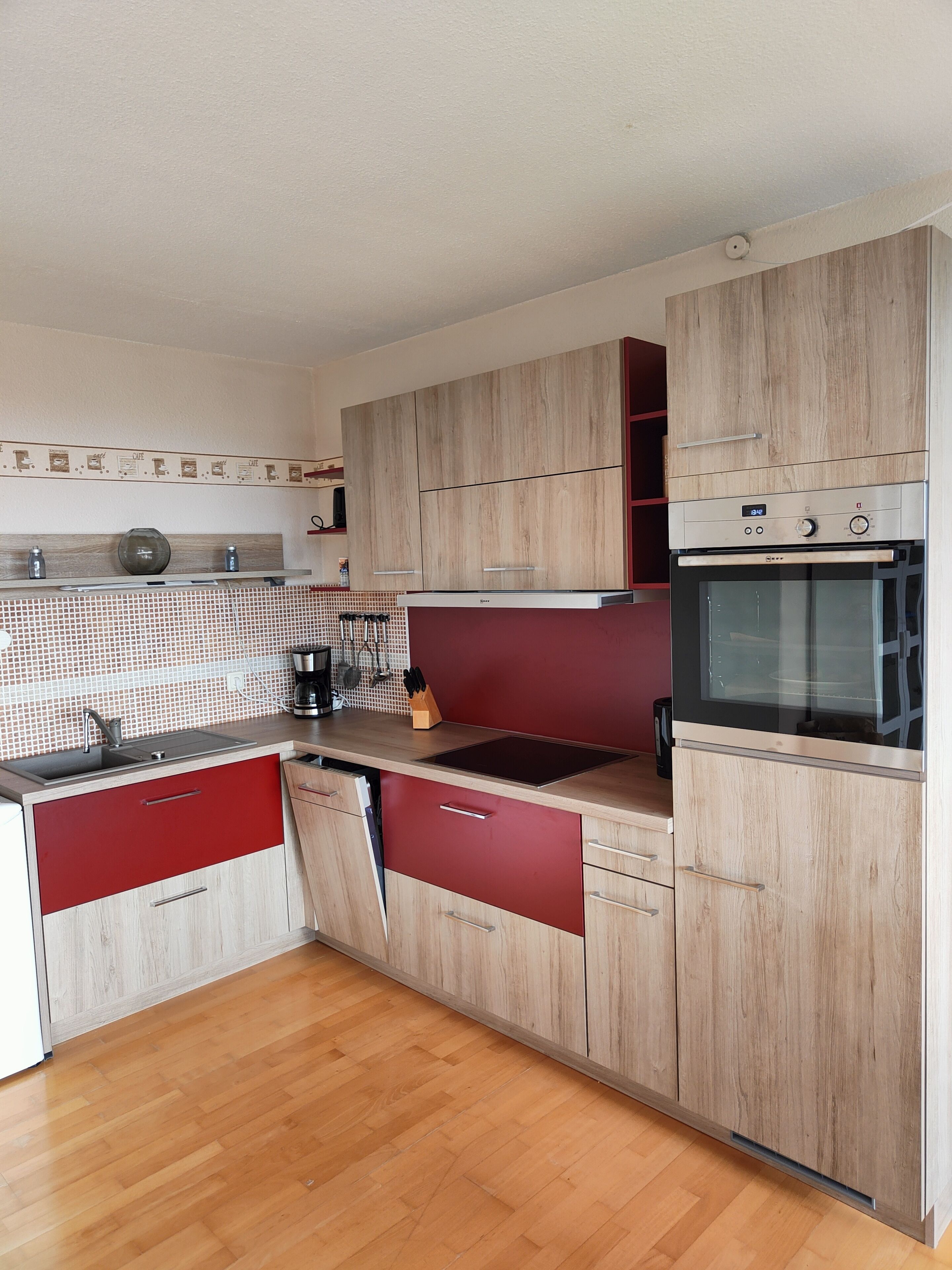 A modern kitchen with wooden cabinets, a built-in oven, and a tiled backsplash.