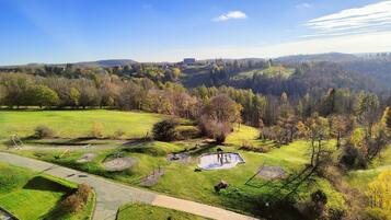 A park with walking paths, playground equipment, and a pond.