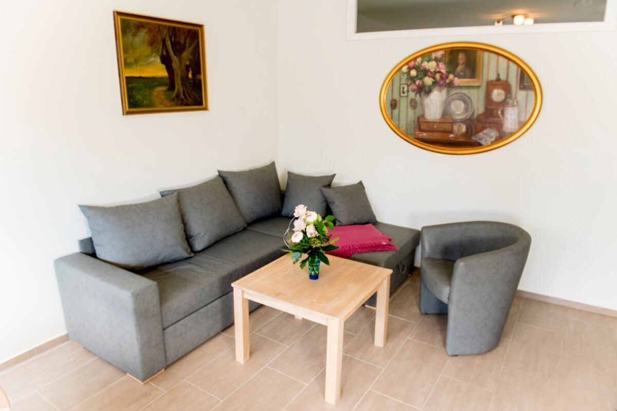 A modern living room with a grey sofa, a wooden coffee table, and a grey armchair.