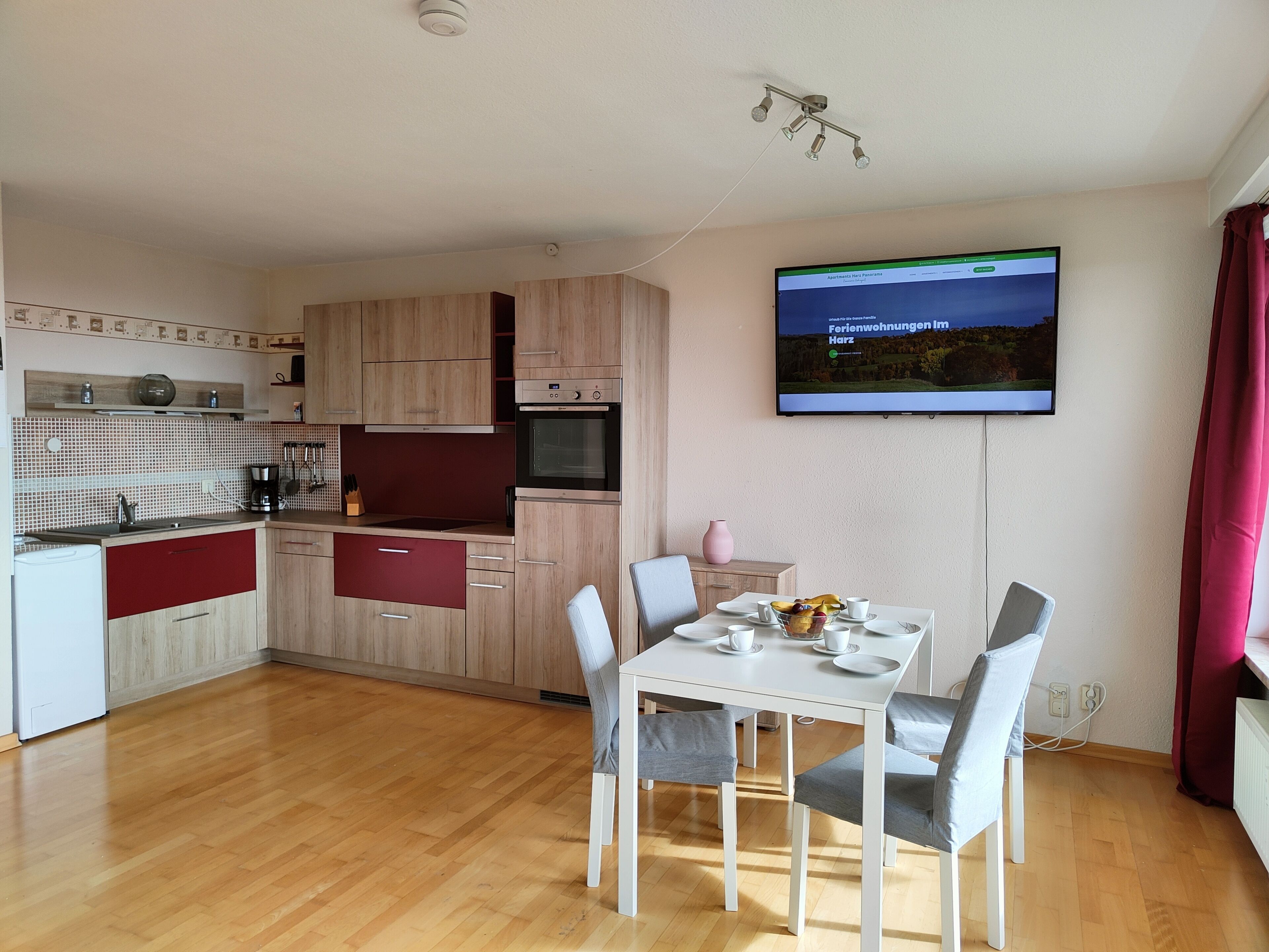 A modern kitchen with wooden cabinets, a built-in oven, and a dining area with a table and chairs.