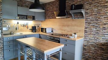 A modern kitchen with a central island, a built-in oven, a microwave, and a coffee maker.