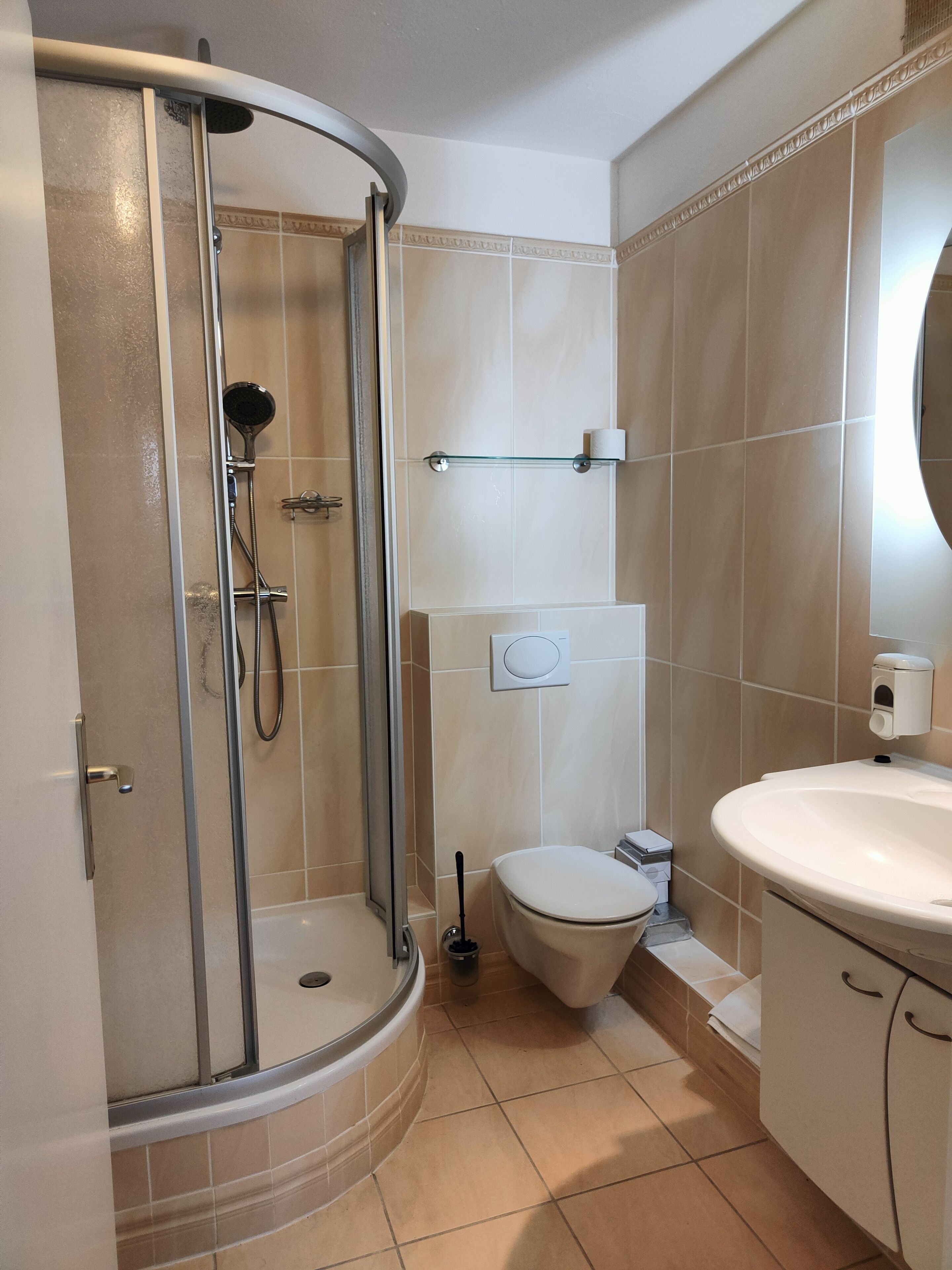 A bathroom with a glass-enclosed shower, a toilet, and a sink.