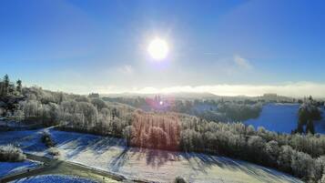 A panoramic view of a snow-covered landscape with a clear sky and a bright sun.