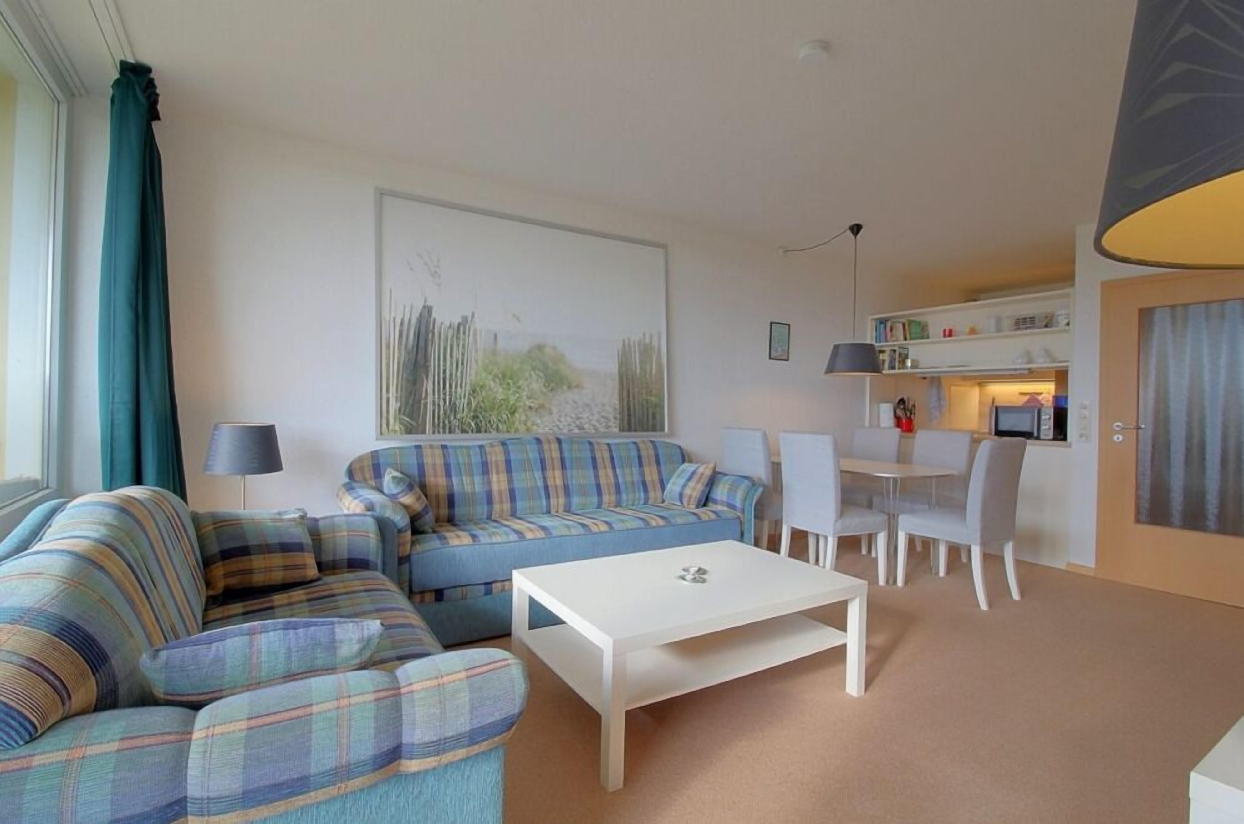 A living room with a sofa, a coffee table, and a dining area with chairs and a table.