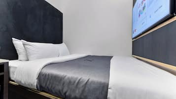 Een moderne hotelkamer met een bed, een aan de muur bevestigde televisie en uitzicht op de lucht.